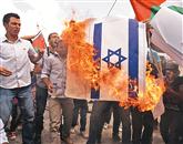 Palestinci so včeraj v bližini Ramale med čakanjem na odločitev v New Yorku zažgali izraelsko zastavo Foto: Reuters