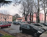 Parkirišče pri Triglavu bo občanom na voljo le še do konca januarja, potem bo namenjeno le gostom rezidence Kraški biser (roza stavba na desni strani, na levi je občinska stavba, nizka bela stavba v sredini pa je komunalno podjetje) Foto: Marica Uršič Zupan